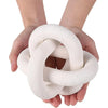 A pair of hands holds a white, handcrafted wood knot decor item.