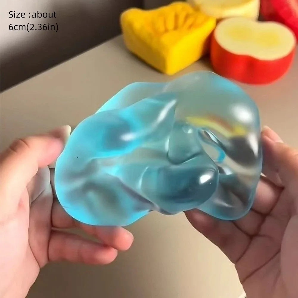 A hand holds a translucent blue stress ball next to various colored fruits.