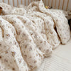 A soft, cream-colored floral muslin baby blanket draped on a surface.