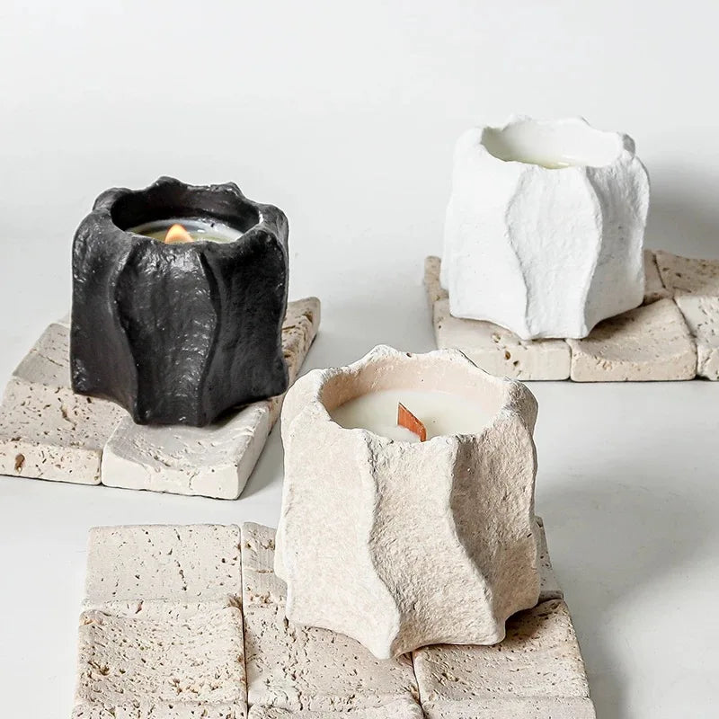 Three concrete candle holders with wavy edges are displayed on a white surface.