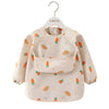 A beige children's waterproof long sleeve feeding bib with a catch pocket decorated with small fruit illustrations.