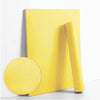 A roll of yellow self-adhesive peel-and-stick wallpaper lying next to a circular swatch.