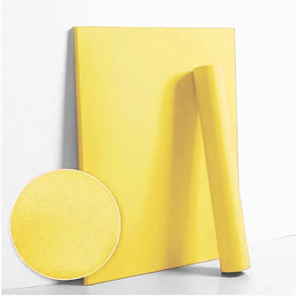 A roll of yellow self-adhesive peel-and-stick wallpaper lying next to a circular swatch.