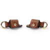 A brown leather shoulder strap with a brass buckle and gold-tone hardware.