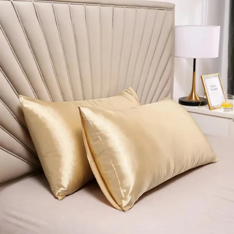 Funda de almohada de satén dorado y plisada con una lámpara blanca en una mesita de noche.