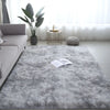 A fluffy gray luxury velvet carpet in a modern living room setting with a plant and decorative items.