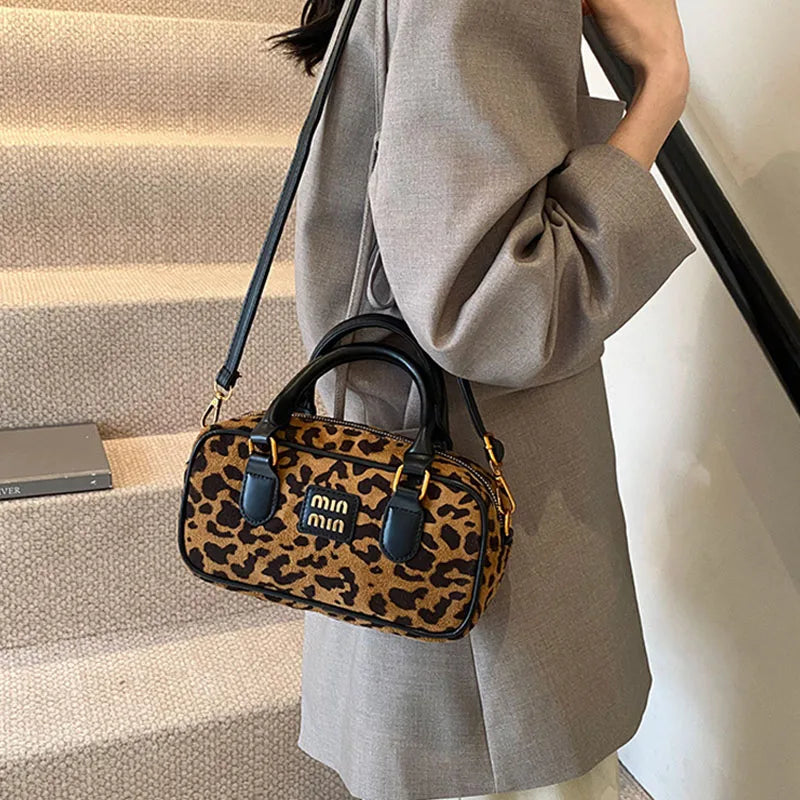 A woman holds a brown leather mini min bag with a leopard print pattern while standing on a staircase.