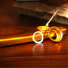 A close-up of a gold-colored aluminum kazoo with a silver membrane diaphragm resting on a wooden surface.