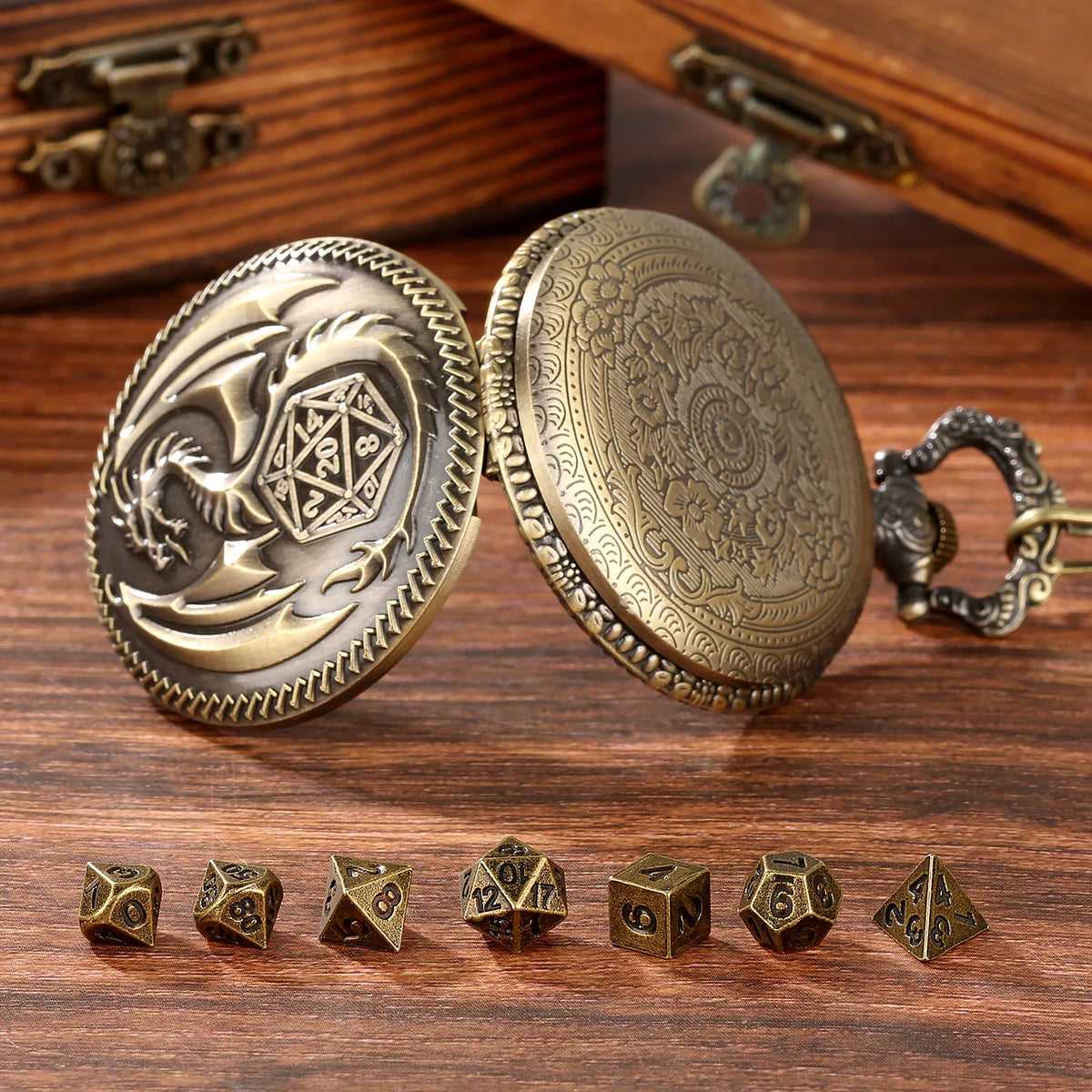 A pair of antique brass dragon-themed pocket watch dice cases with seven metal polyhedral dice resting on dark wood.