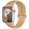 A silver Apple Watch is shown with a tan silicone sport band on a white background.