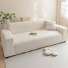 A cream colored plush sofa with a light beige rug and decorative pillows in a bright room.