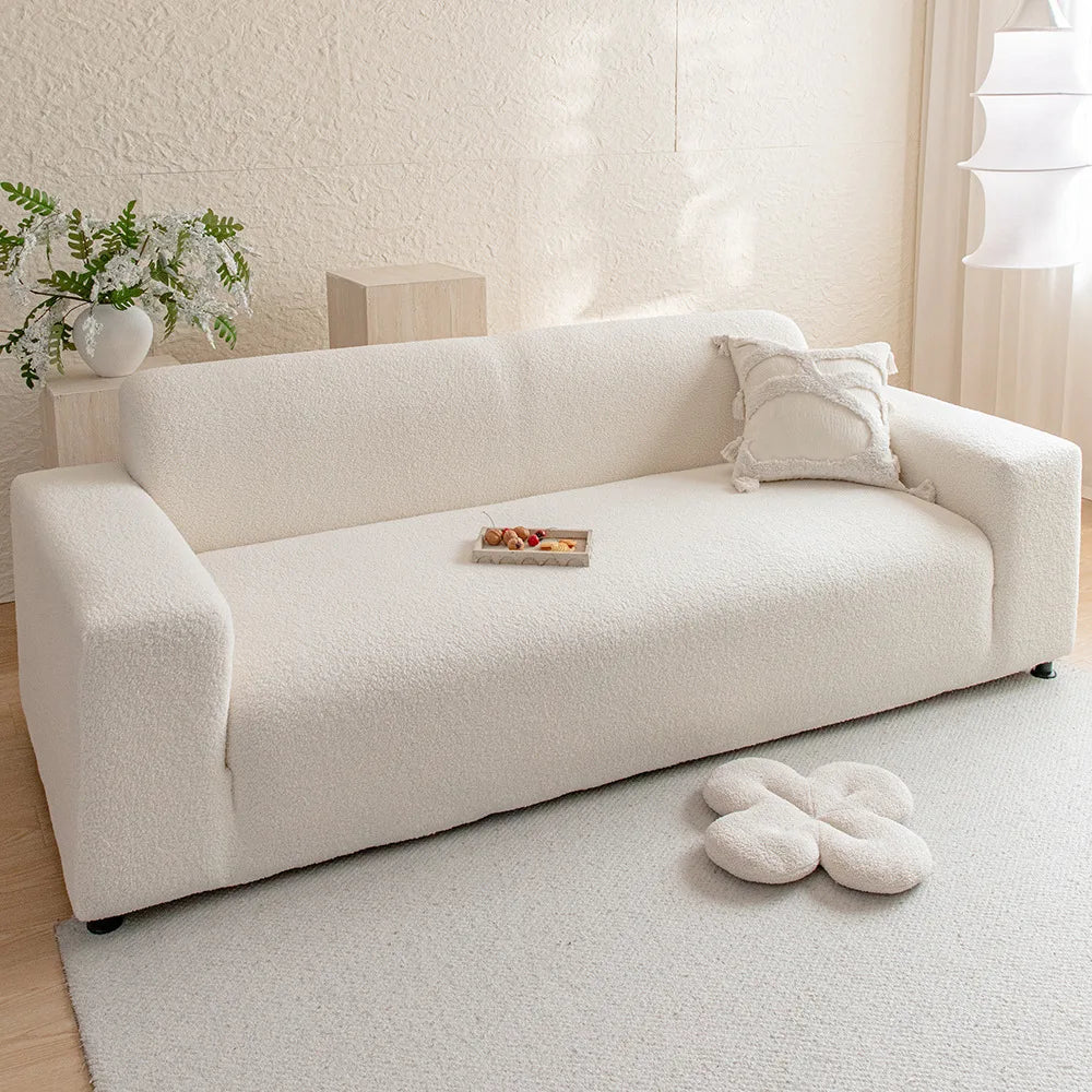 A cream colored plush sofa with a light beige rug and decorative pillows in a bright room.