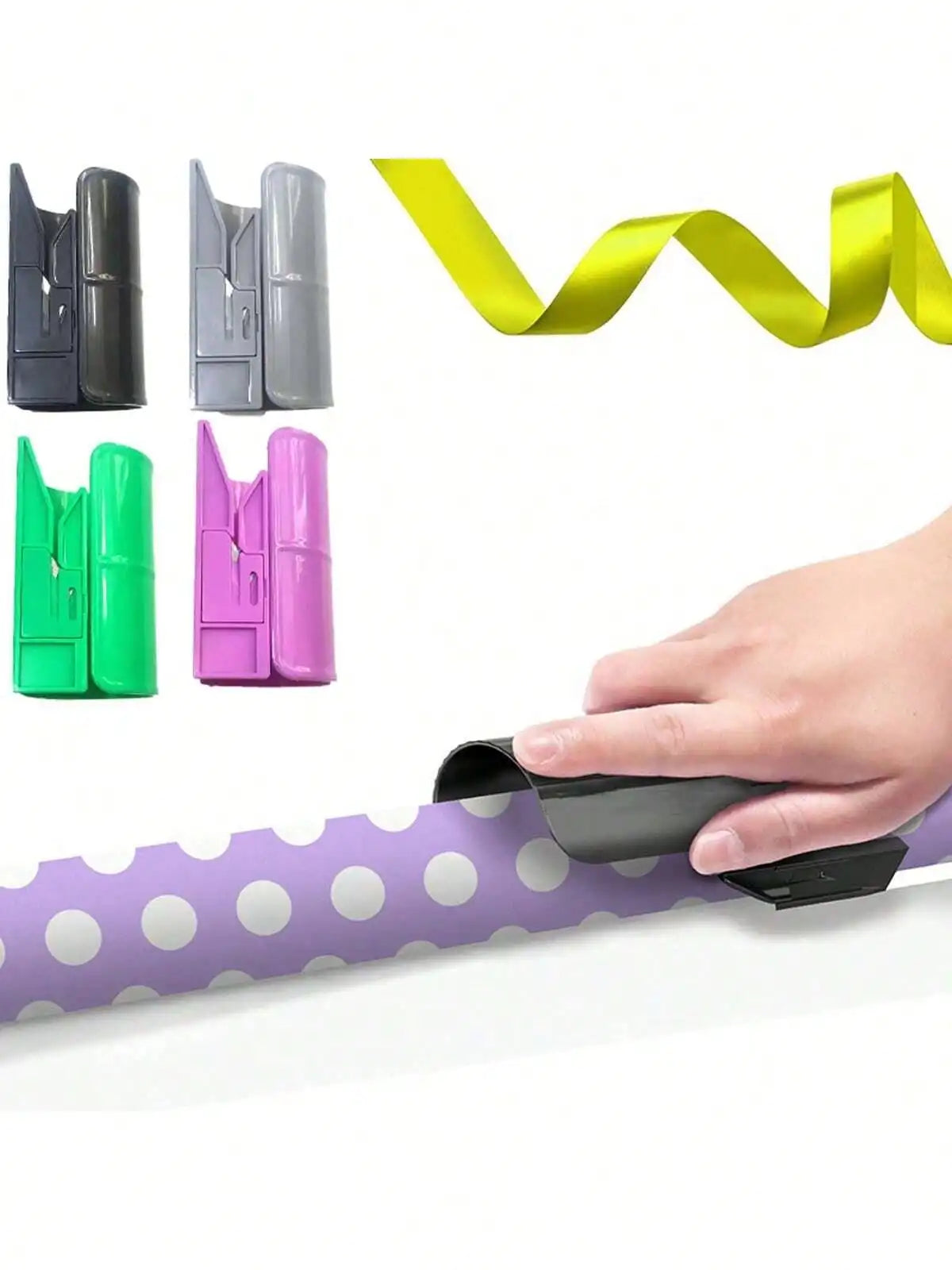 A hand is shown using a portable wrapping paper cutter with a sliding blade to cut a purple polka-dot paper roll.