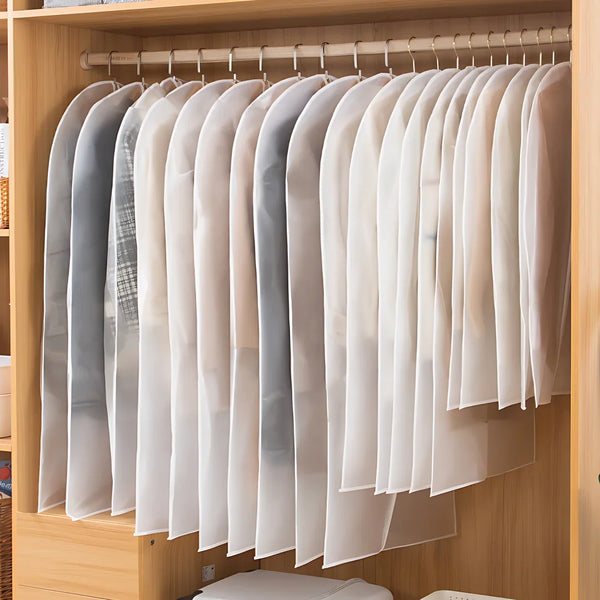 A row of sheer white and translucent garment bags are hanging in a wooden closet rack.