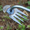 A close-up of a stainless steel weeding tool with a curved handle and multiple prongs for root removal.
