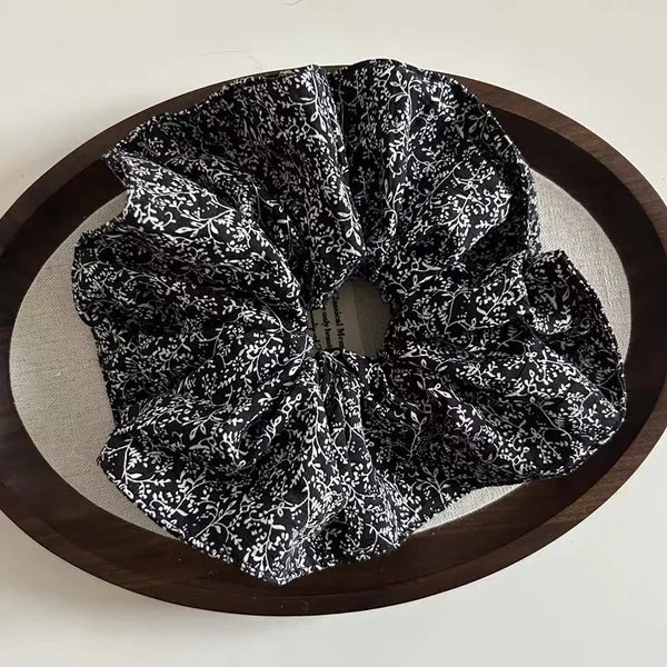 Un moño de tela estampado de leopardo en blanco y negro se exhibe en un plato de madera oscura.