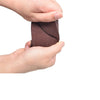 A brown kitchen sponge brush is shown being held by a hand, demonstrating its durability and ability to cut into gaps.