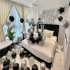 A bedroom decorated for a birthday party with black and silver balloons and foil numbers