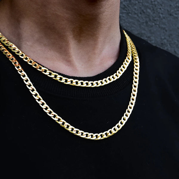 Primer plano de un collar de eslabones cubanos de oro usado alrededor del cuello contra una camisa negra.