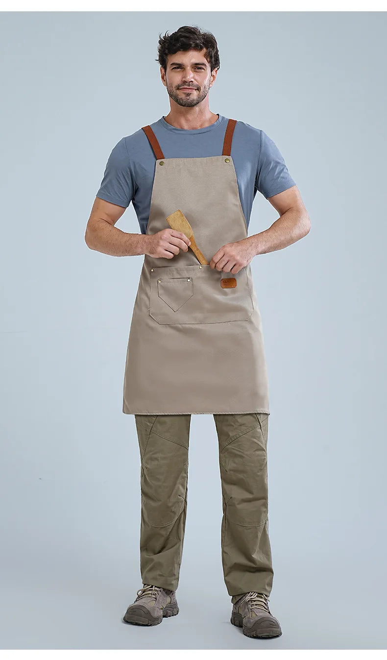 A man wearing a beige waterproof kitchen apron over a gray shirt and olive green pants.