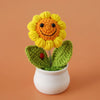 Handcrafted crochet sunflower with green leaves growing in a white pot
