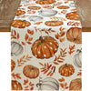 Linen table runner featuring an orange and white fall pumpkin and maple leaf pattern on a cream background.