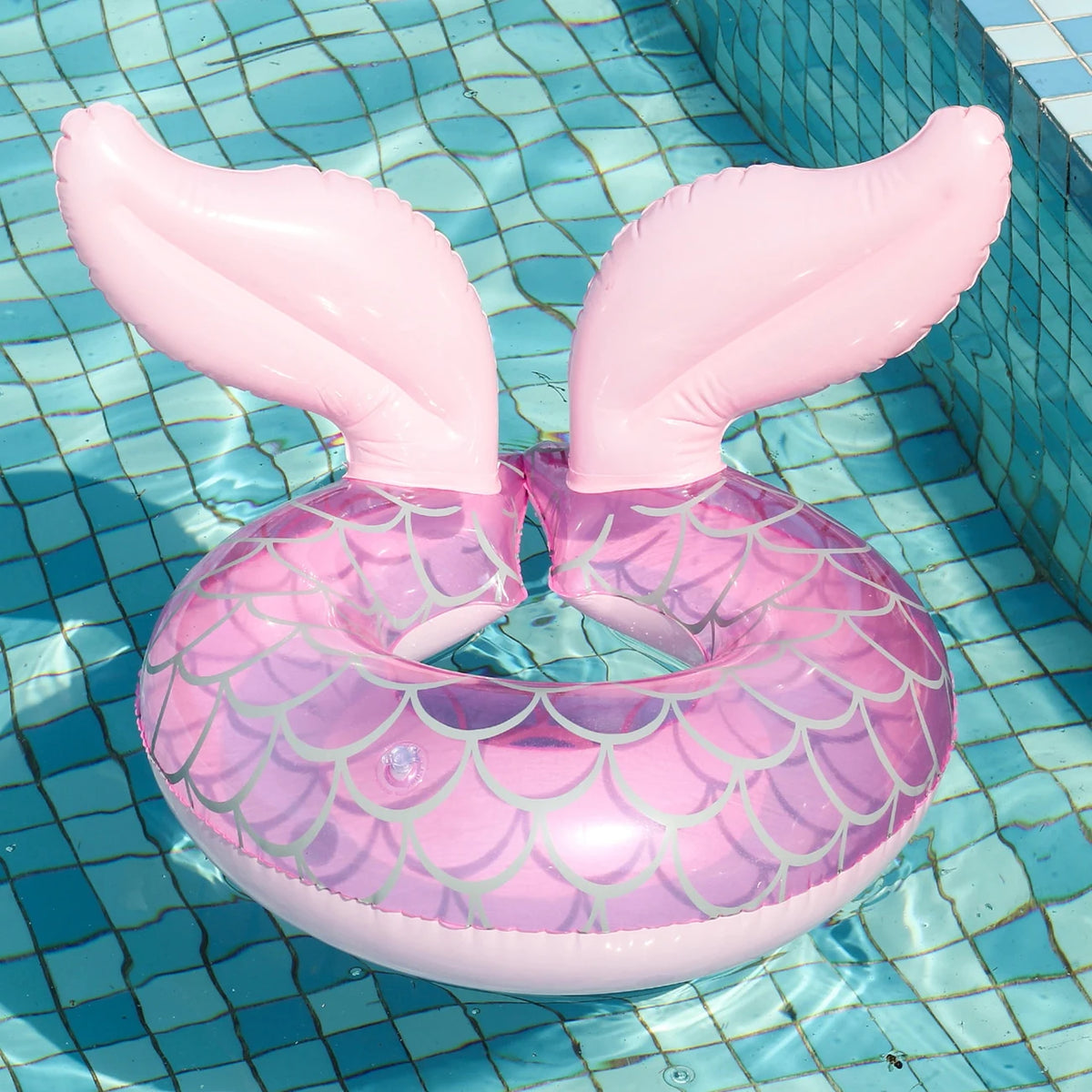 Pink inflatable swim ring with wing-like fins floating in blue water.