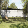 A large mesh fly net canopy is set up over a patio area with a table and chairs, surrounded by trees.