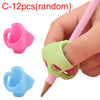 A hand is holding a pink pencil with a green ergonomic grip trainer, showing two different colored grips.