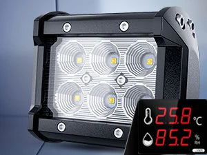A black LED flood light pod with four bright yellow light sources is shown against a gray background.