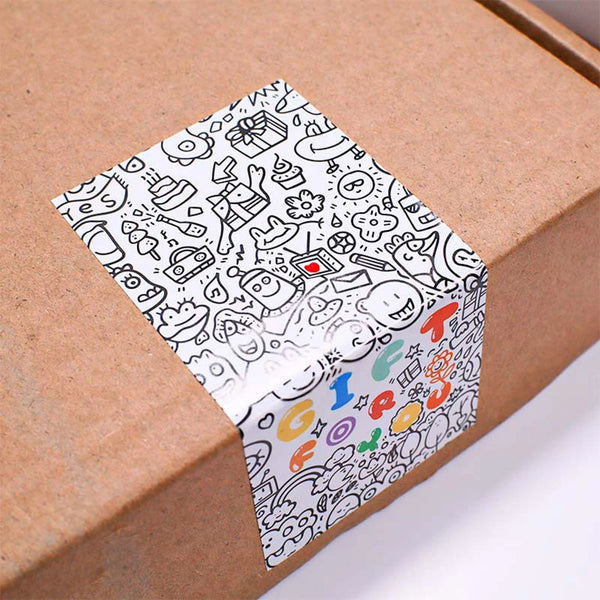 A sheet of rectangular thank you sealing stickers with various doodle and hand-drawn symbols on a brown cardboard box.