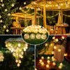 Outdoor fairy lights strung across a wooden pergola and draped on greenery, illuminating a festive outdoor setting.