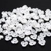 A pile of 100 white acrylic pearl spacer beads shaped like small flowers for jewelry making