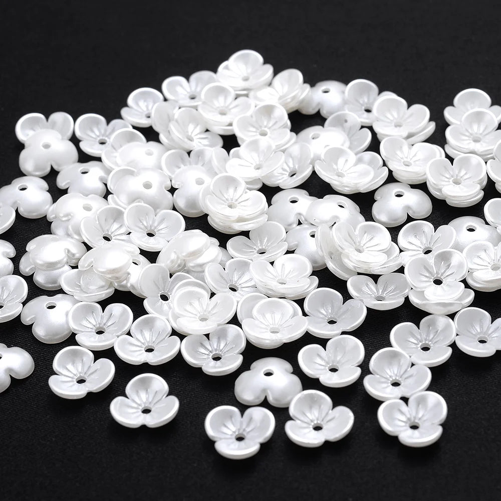 A pile of 100 white acrylic pearl spacer beads shaped like small flowers for jewelry making