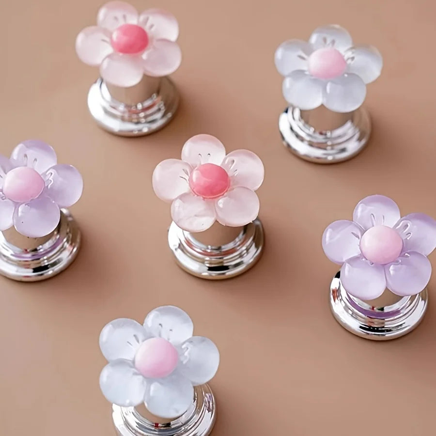 A collection of pink and white floral toilet flush handles with silver bases.