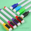 Eight fine tip whiteboard markers in assorted colors and white tips are arranged on a green surface.