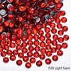 A close-up view of red faceted rhinestones scattered on a white background.