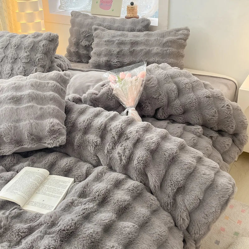 A gray ultra-soft plush 4-piece bedding set featuring textured, fluffy fabric pillows and a blanket.