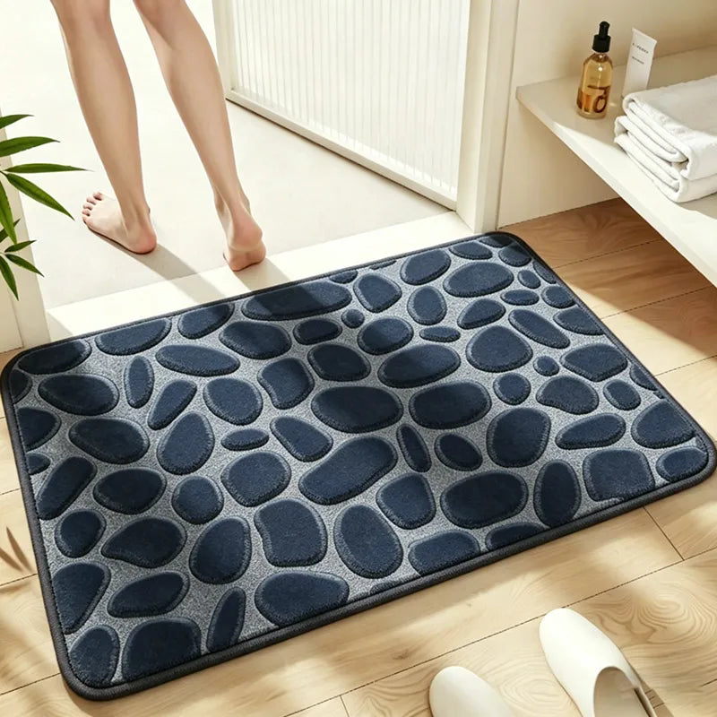 A dark blue plush non-slip bathroom rug with a pebble texture placed on a light wooden floor.