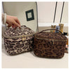 A brown leopard print faux suede cosmetic bag with a gold zipper and hardware displayed on a white surface.