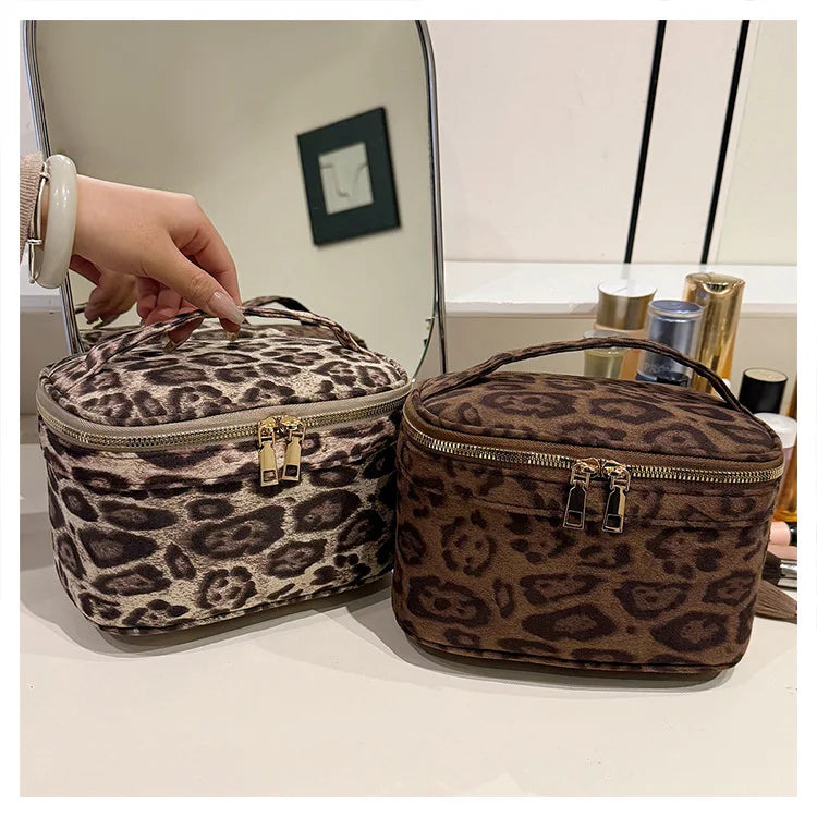 A brown leopard print faux suede cosmetic bag with a gold zipper and hardware displayed on a white surface.