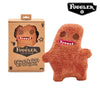 A brown, fuzzy plush toy monster with pink teeth and brown eyes is shown next to its packaging.