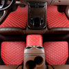 Interior view of a car showing red quilted leather floor mats and a center console with controls.