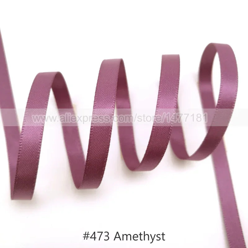 A roll of purple amethyst satin ribbon unwinding against a white background.