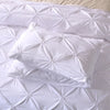 White quilted bedding set featuring a comforter and pillowcases.
