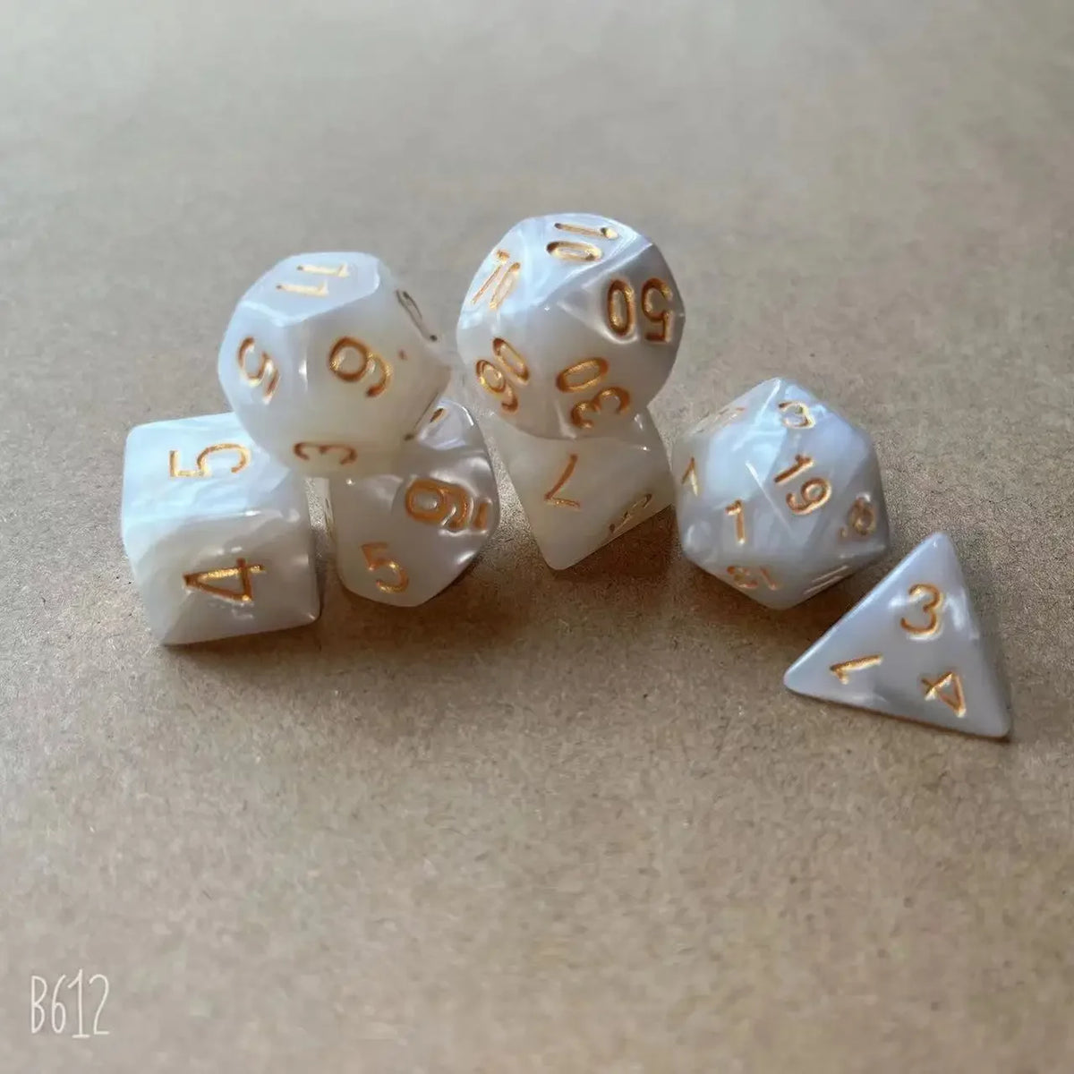 A set of seven white pearl pattern polyhedral dice arranged diagonally on a light brown surface.