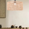 A large woven paper rope pendant lampshade hangs against a light wall, with some dark pottery items on a wooden surface below