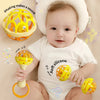 A baby is holding a yellow silicone spinning rattle toy set with an orange ring.