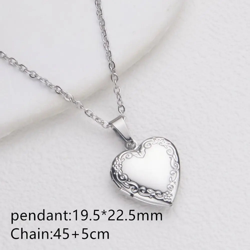 Silver heart locket necklace with a delicate chain resting on a white surface.
