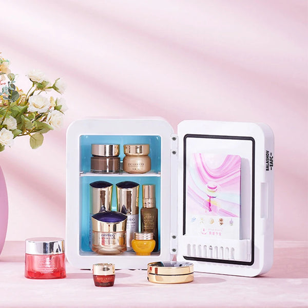 A white compact LED makeup fridge with a mirror displays various cosmetic products in an illuminated interior.